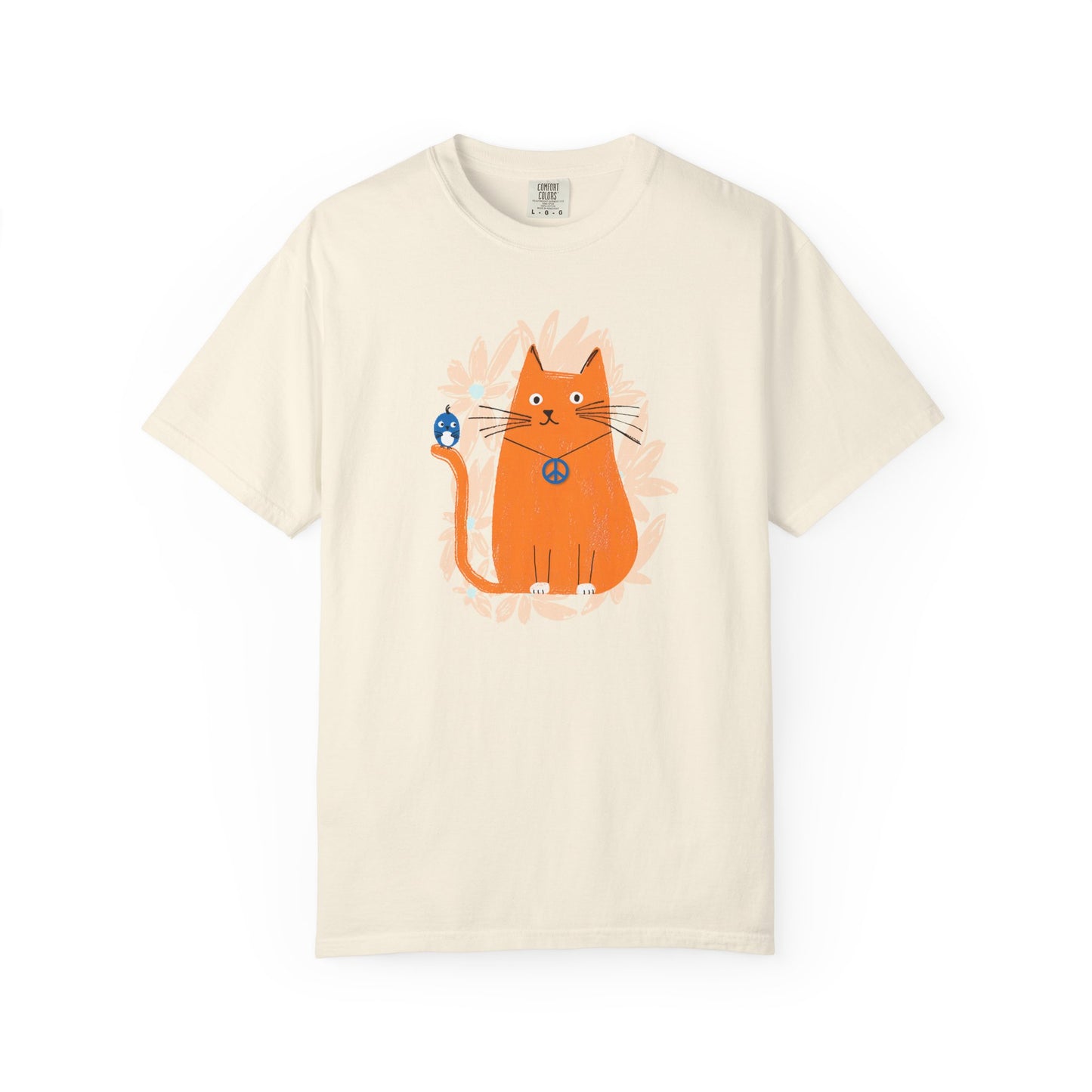 An ivory t-shirt featuring an orange cat wearing a "peace" sign necklace; perched on the cat's tail is a cute blue bird. A spray of pale orange flowers in the background.