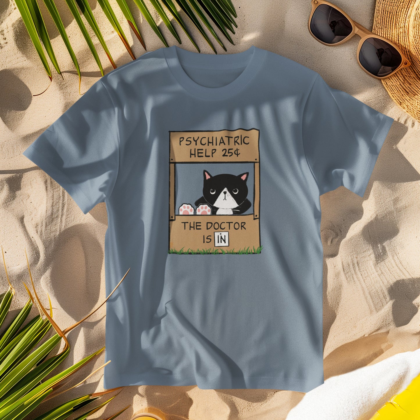 Blue t-shirt with a graphic of a cat with feet up on the counter of a booth showing signs reading "Psychiatric Help 25 cents" and "The Doctor is IN"