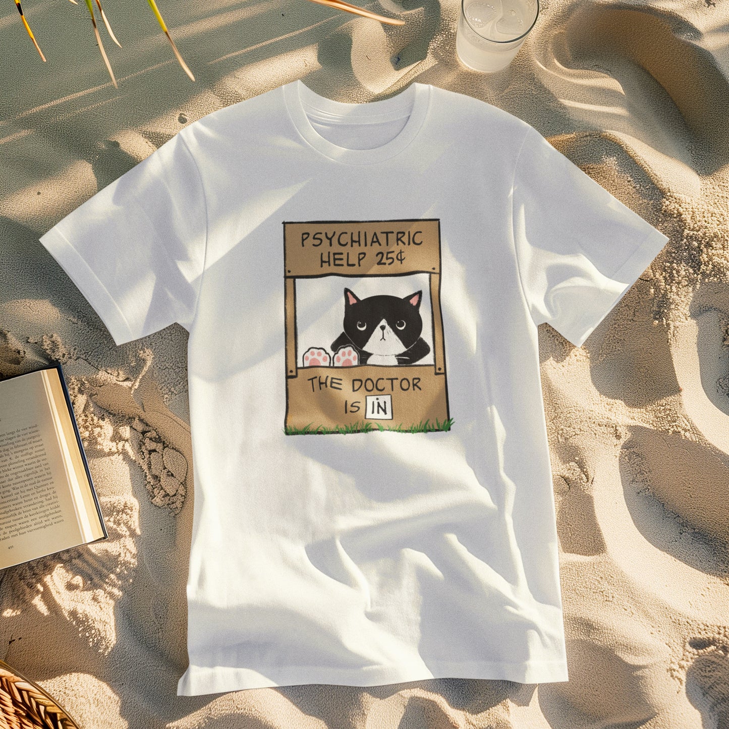 a white t-shirt with a graphic of a cat with feet up on the counter of a booth showing signs reading "Psychiatric Help 25 cents" and "The Doctor is IN"
