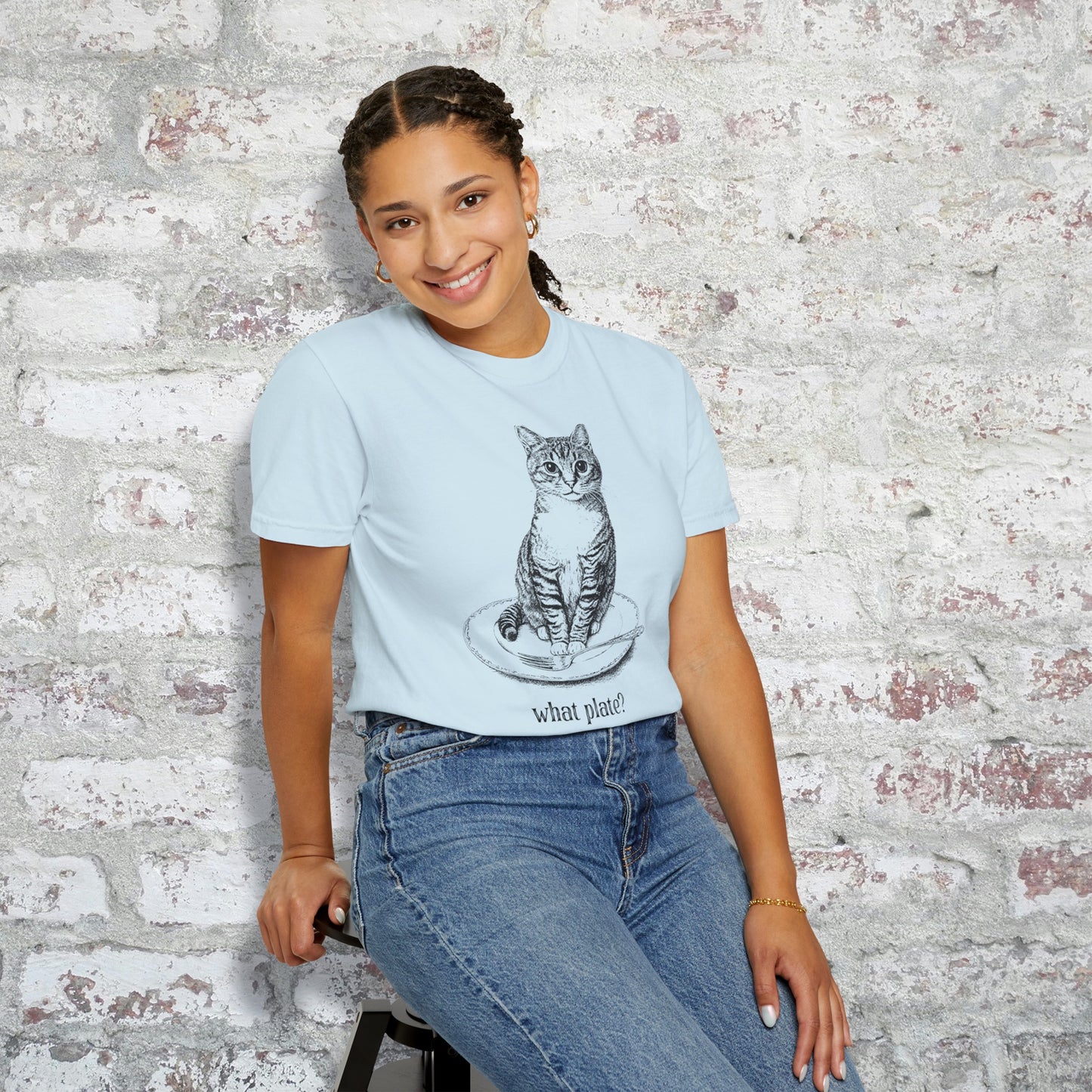 person wearing a light blue t-shirt with a detailed drawing of a cat on a dinner plate with fork, with text "What Plate?"