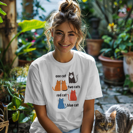 woman wearing a white graphic t-shirt featuring one tuxedo cat, two orange cats, one red cat, and one blue cat