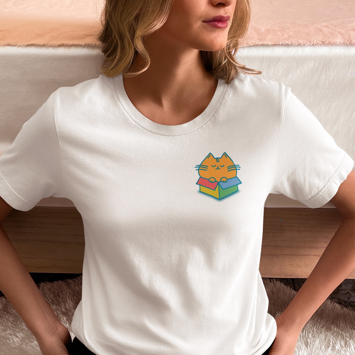 person wearing a white graphic t-shirt with chubby orange cat in a color box on the front of the shirt